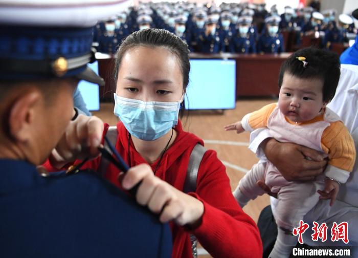 新消防員楊振的妻子彭莉與女兒現(xiàn)場見證丈夫加入“火焰藍”的神圣時刻?！⒅铱?攝